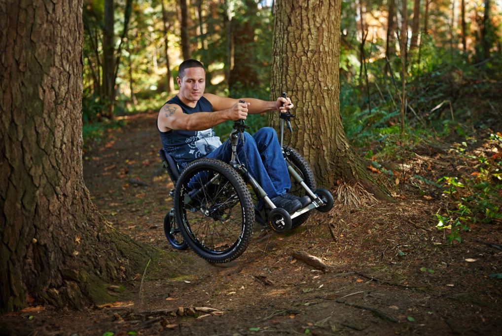 man in a wheelchair going on a hike in the woods